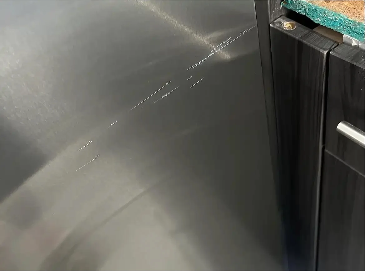 Scratched stainless refrigerator door before repair